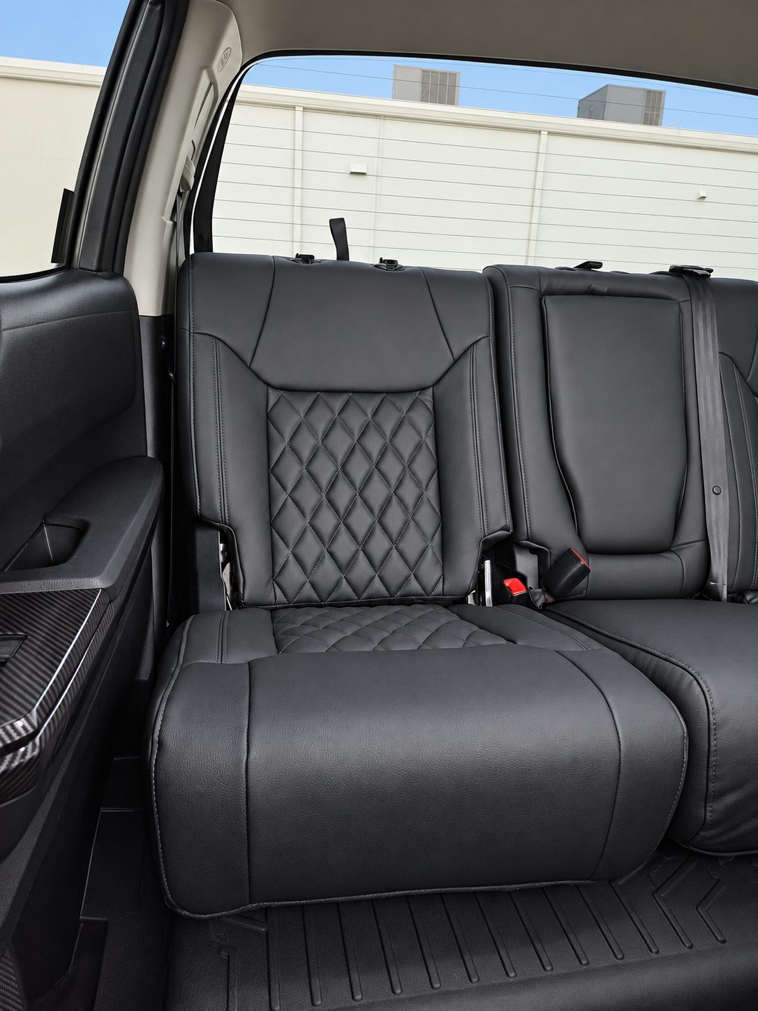 Black vehicle rear seats with diamond-stitched upholstery panels.