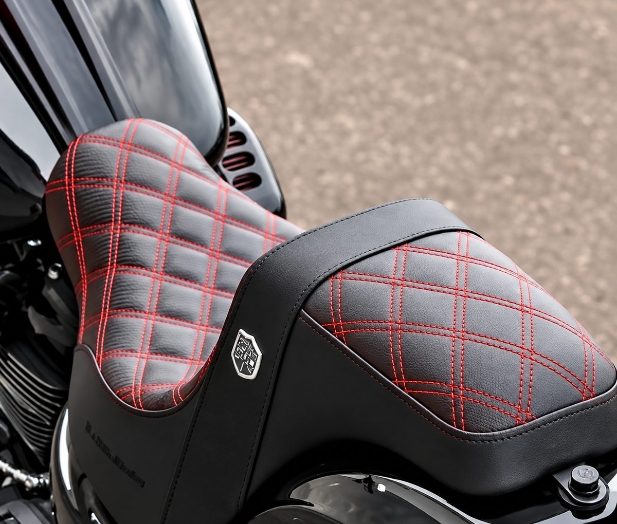 Black motorcycle seat with red double diamond stitching.