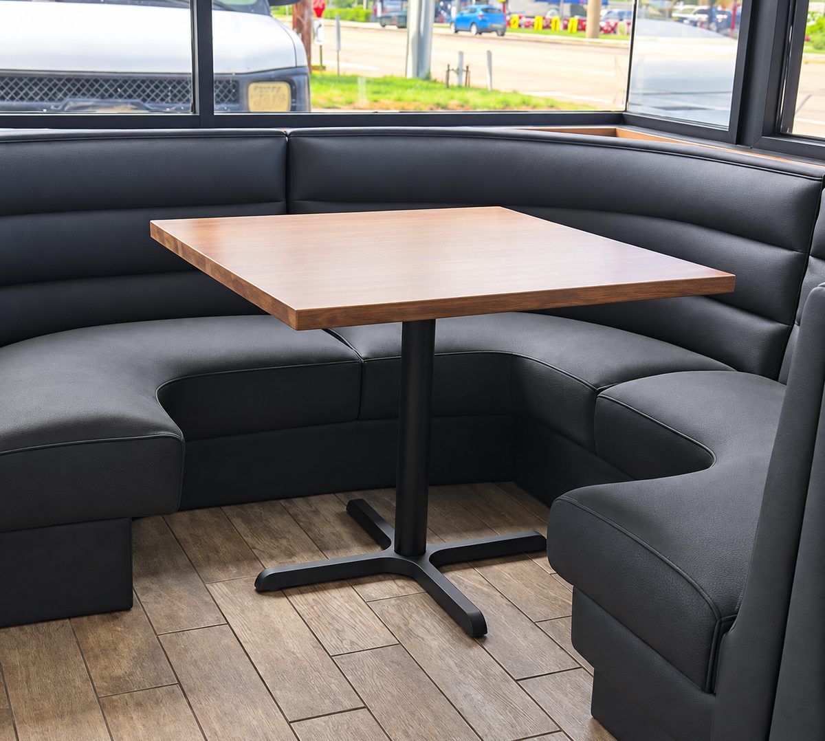 Black channel-stitched corner booth in a restaurant with a square wood table.