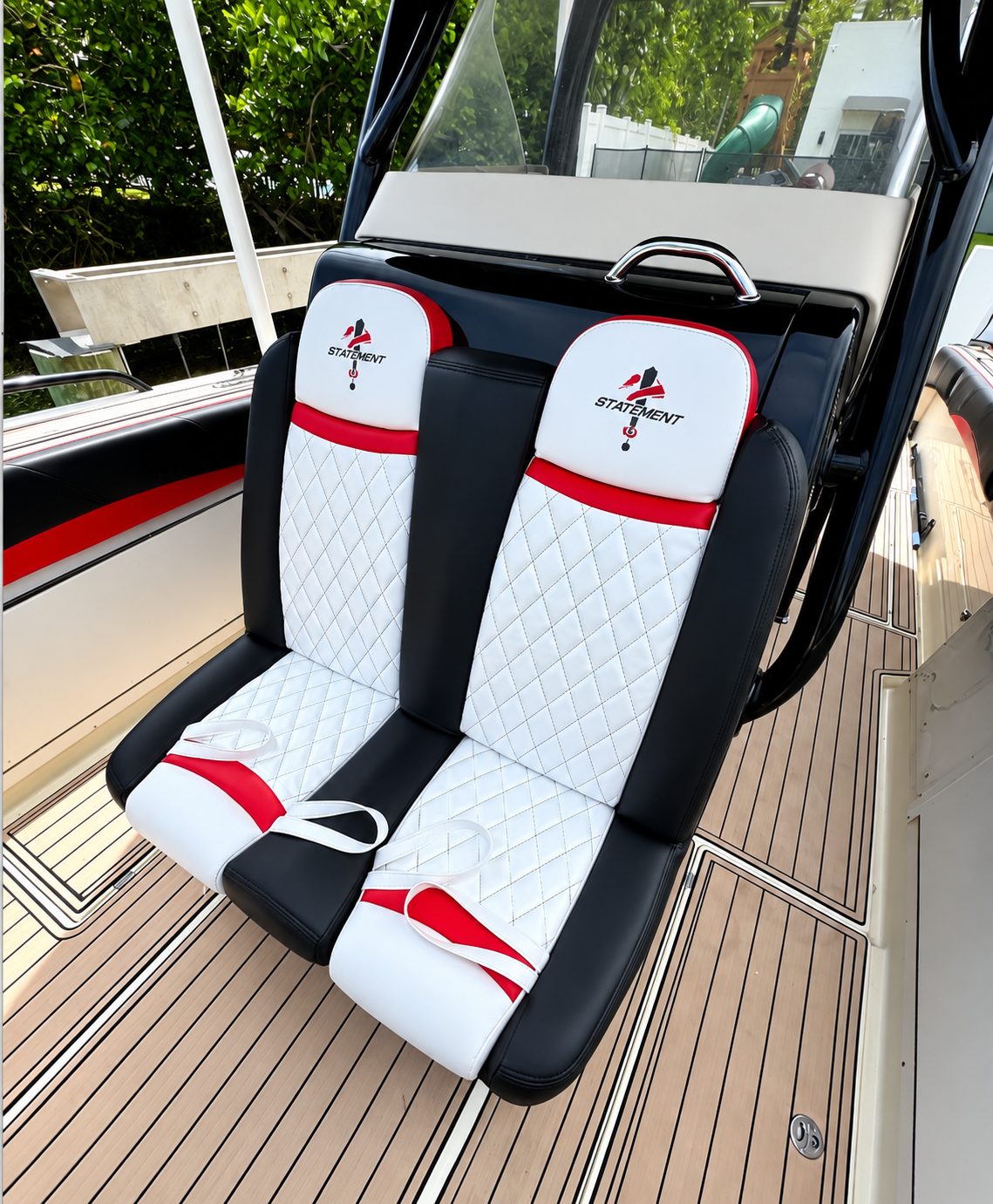 Front view of a pair of boat seats in white diamond-stitched vinyl with black bolsters and red accents.