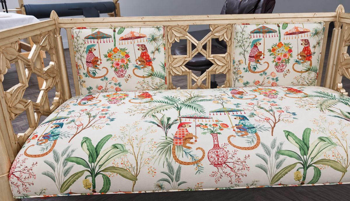 Cream fretwork bench with a seat cushion and back panels in a tropical monkey-print fabric.