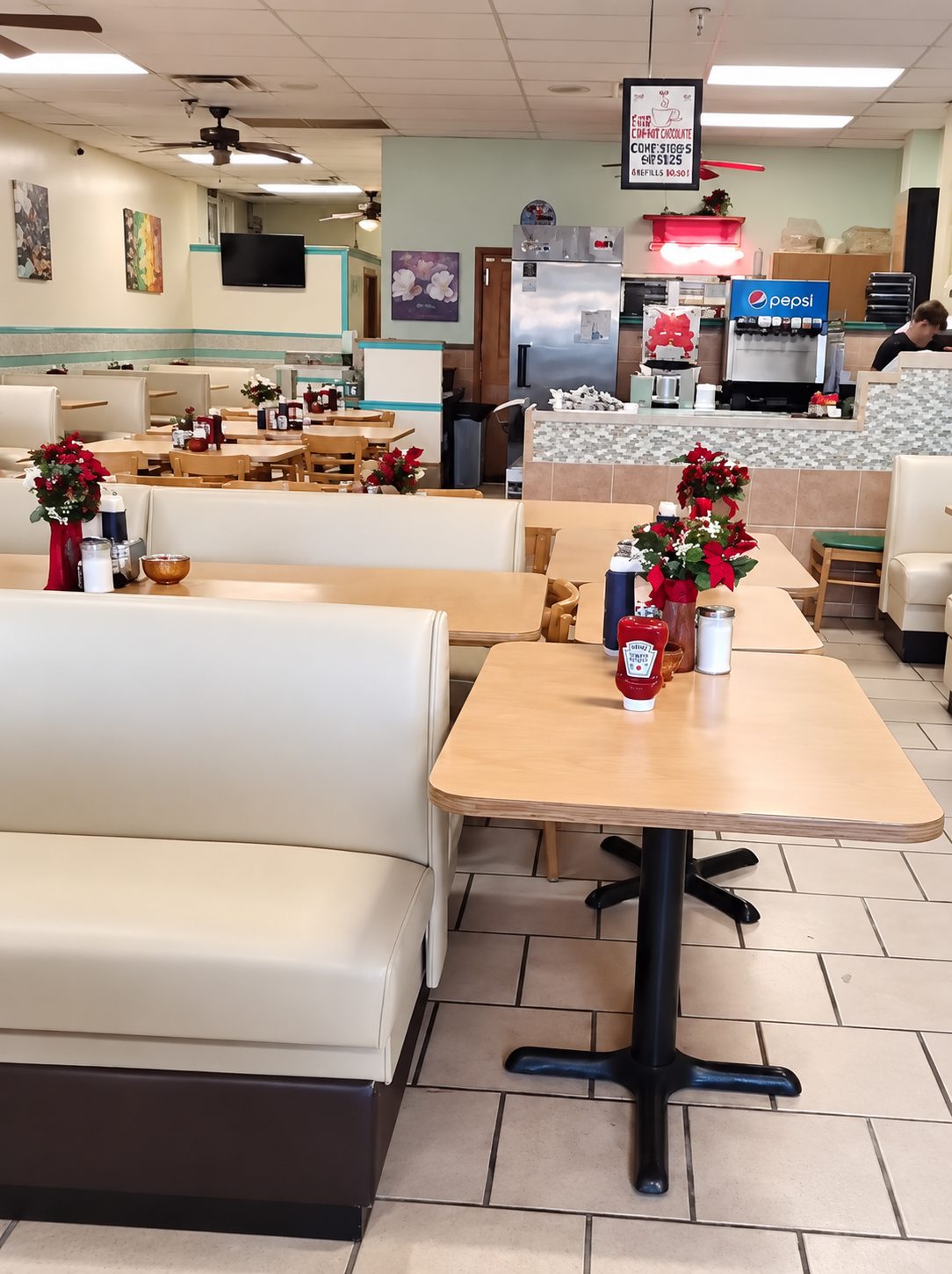 Cream upholstered restaurant booths beside wood tables, looking toward the service counter.