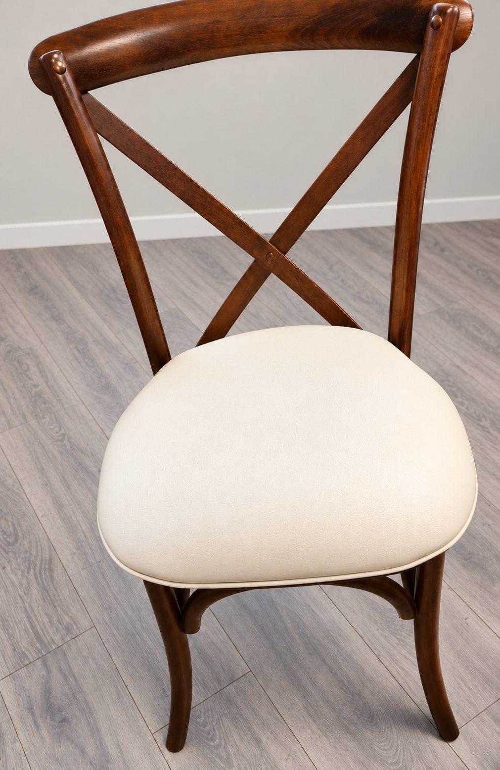 Dark wood cross-back dining chair with a new cream faux-leather seat.