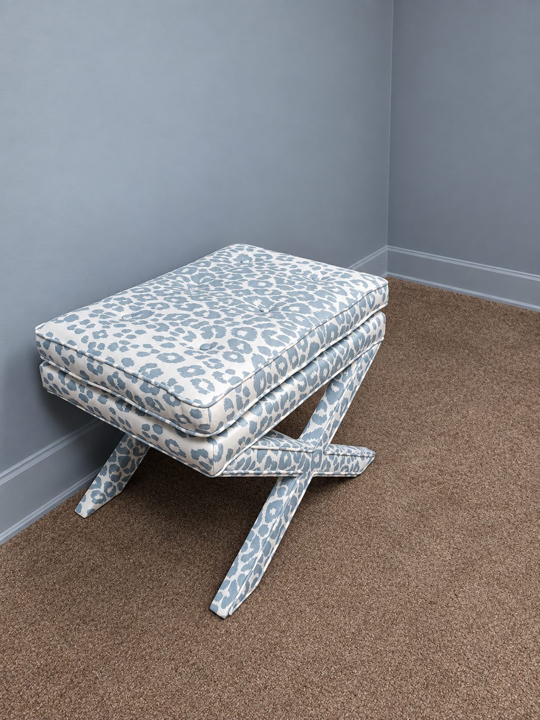 Gray animal-print upholstered ottoman with an X-shaped base.