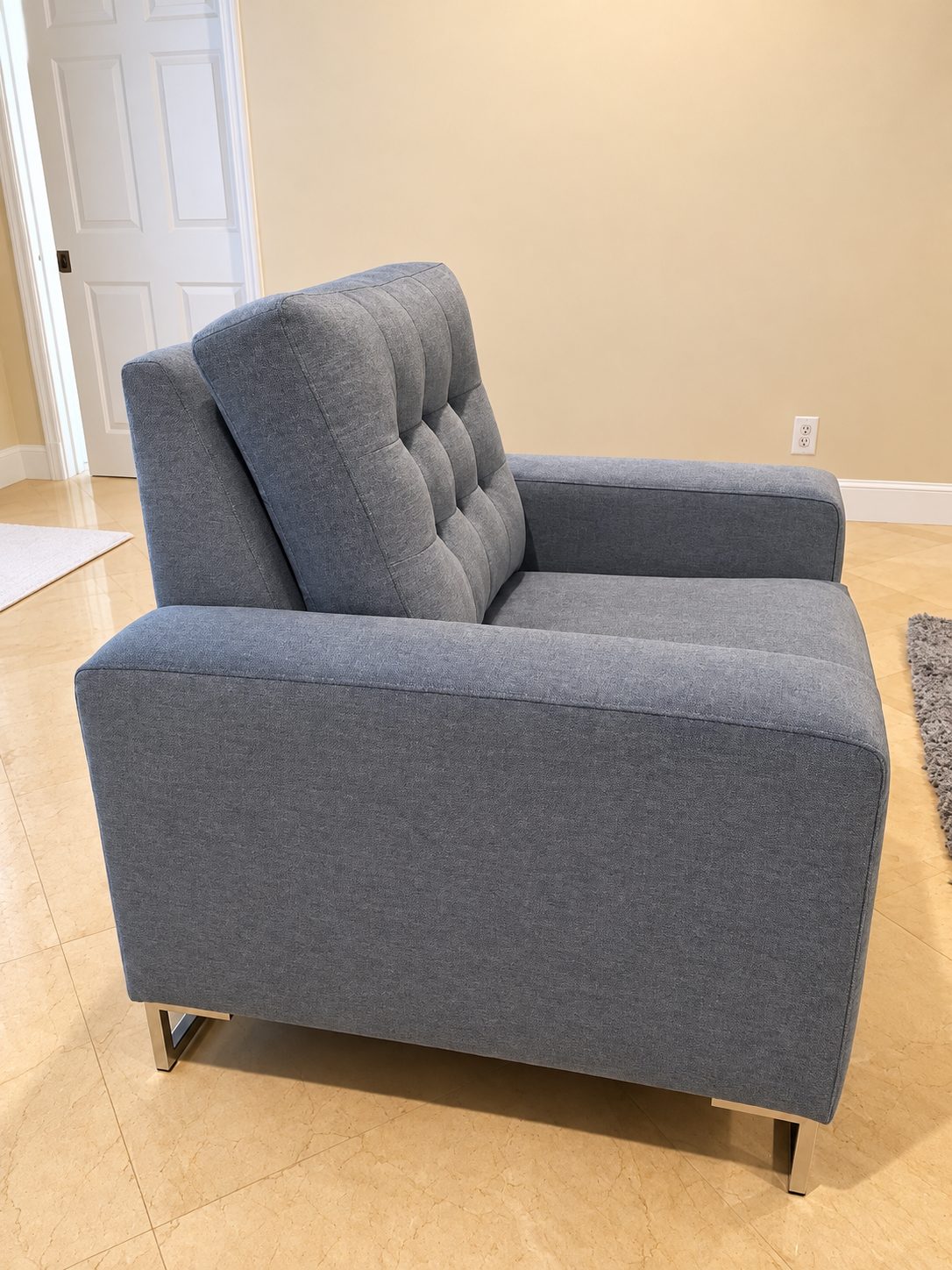 Gray tufted armchair with metal legs.