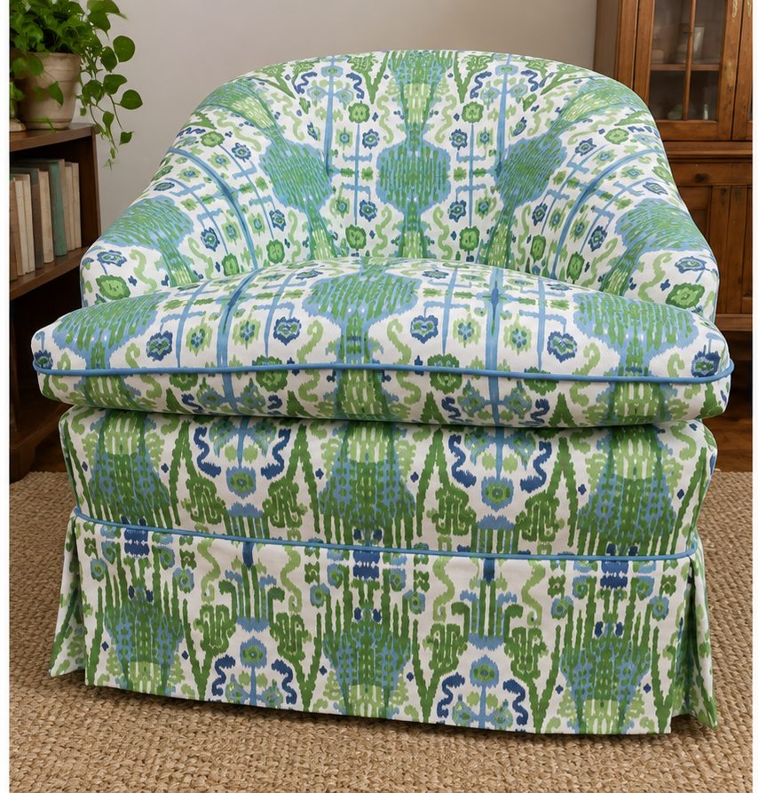 Green and blue ikat-patterned armchair with blue piping and a skirted base.
