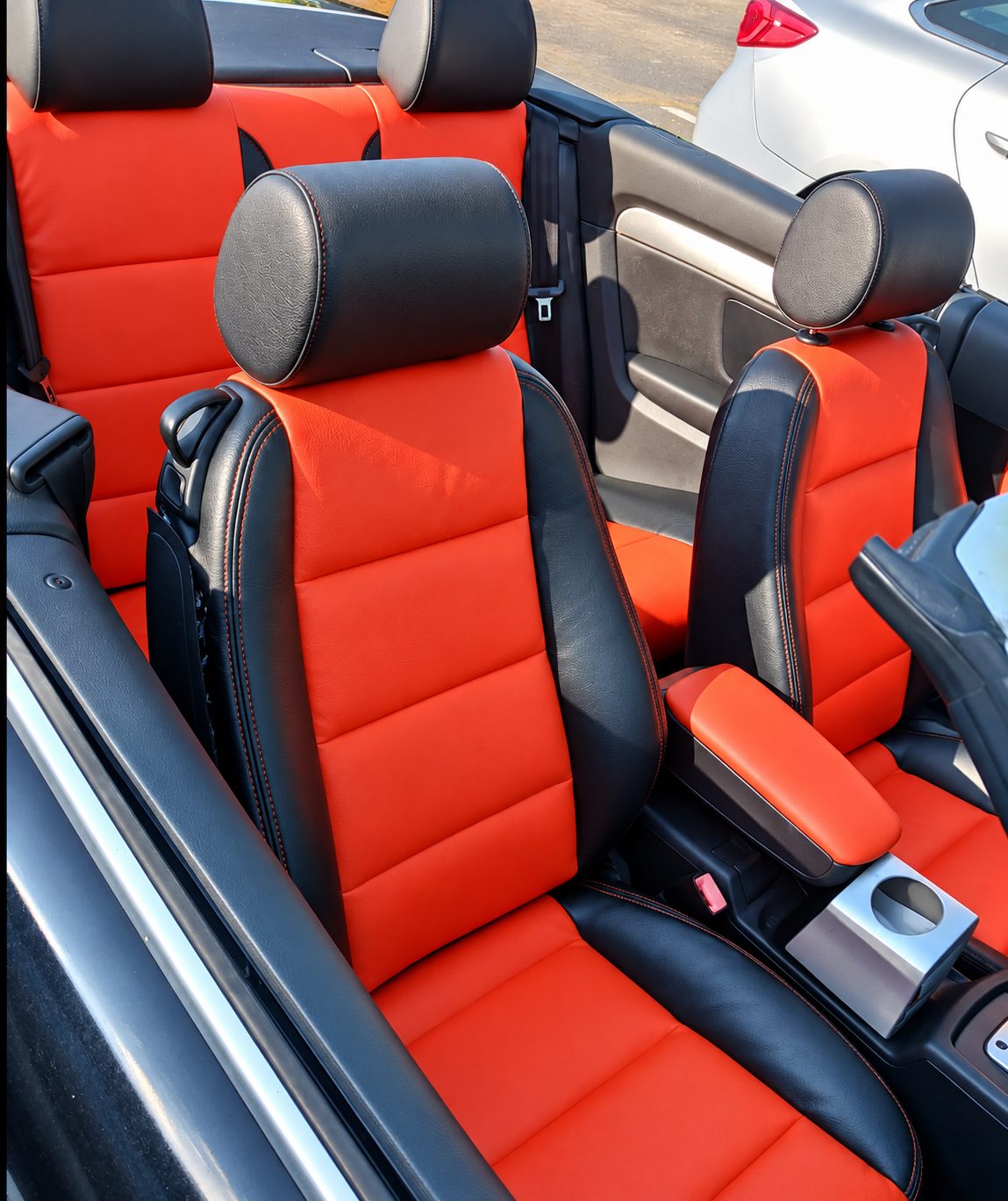 Orange and black upholstered front seats in a convertible.