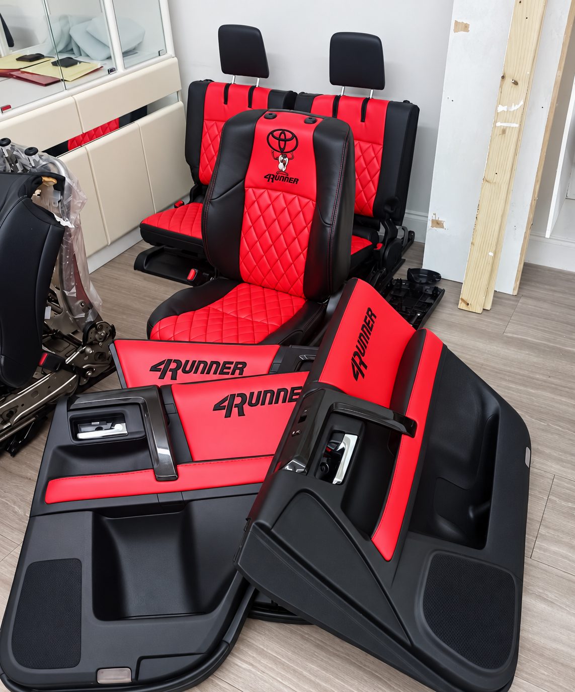 Red and black diamond-stitched Toyota 4Runner seats and door panels in the workshop.