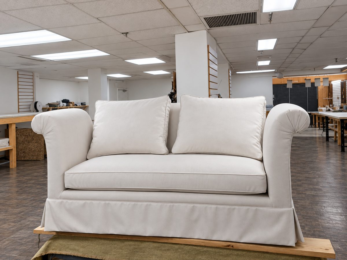 White skirted loveseat with rolled arms and matching cushions.
